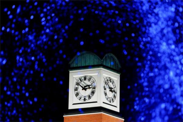  A carillon tower is framed by water colored by blue light. 